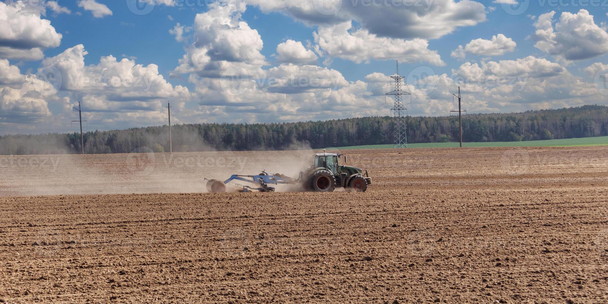 tractor cultivator or seeder plows the land, prepares for crops. dust on field photo