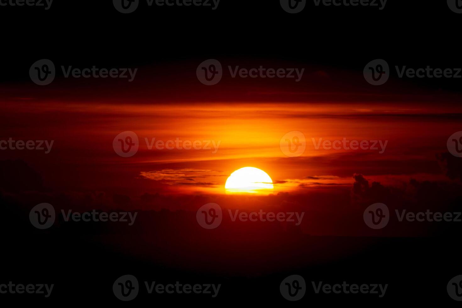 Glowing red sunset. Setting sun behind the clouds. Sun in the dusk photo