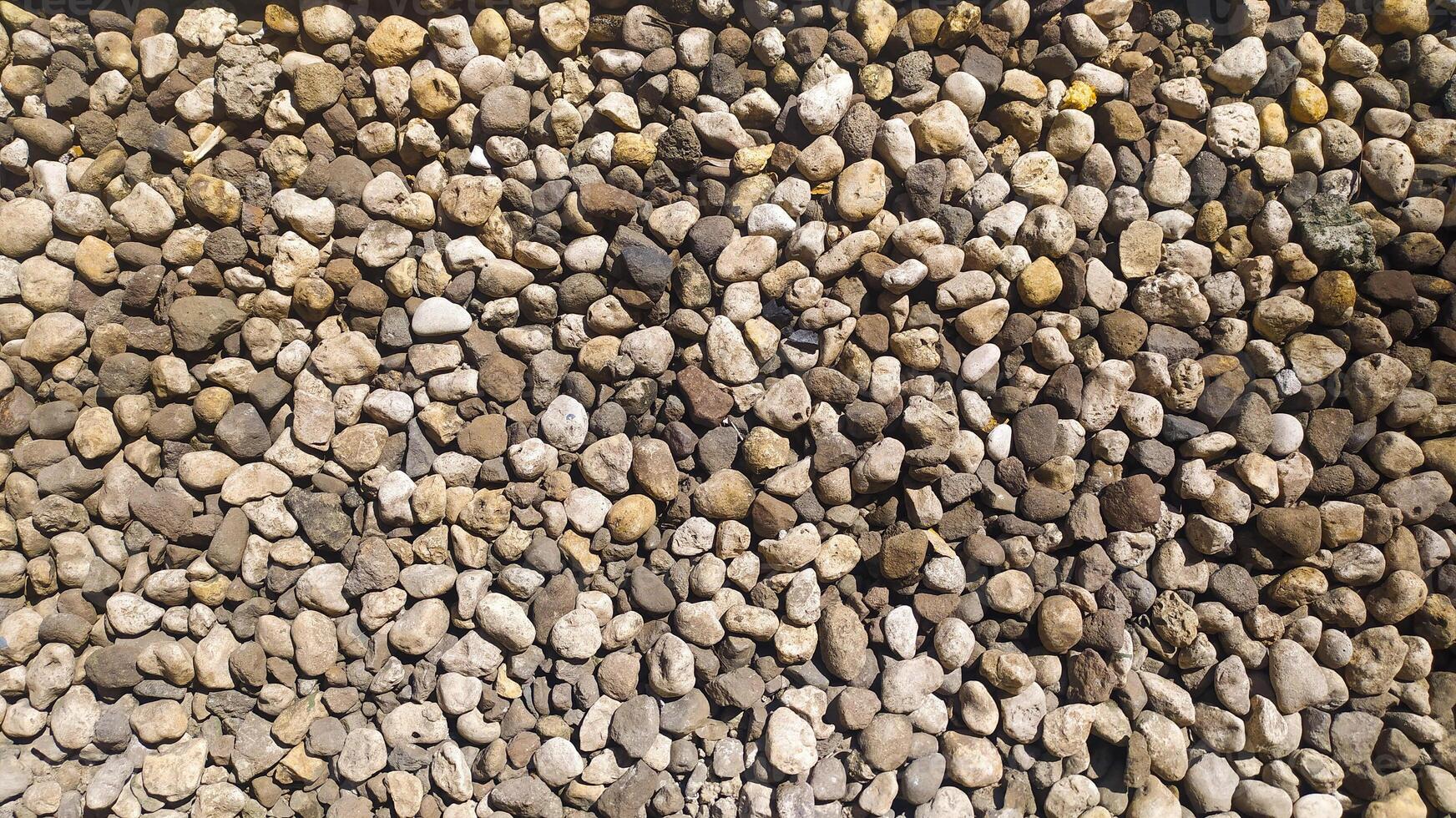 Pebbles piled up and scattered on the ground on a road create an interesting texture, suitable for photo backgrounds and texture designs