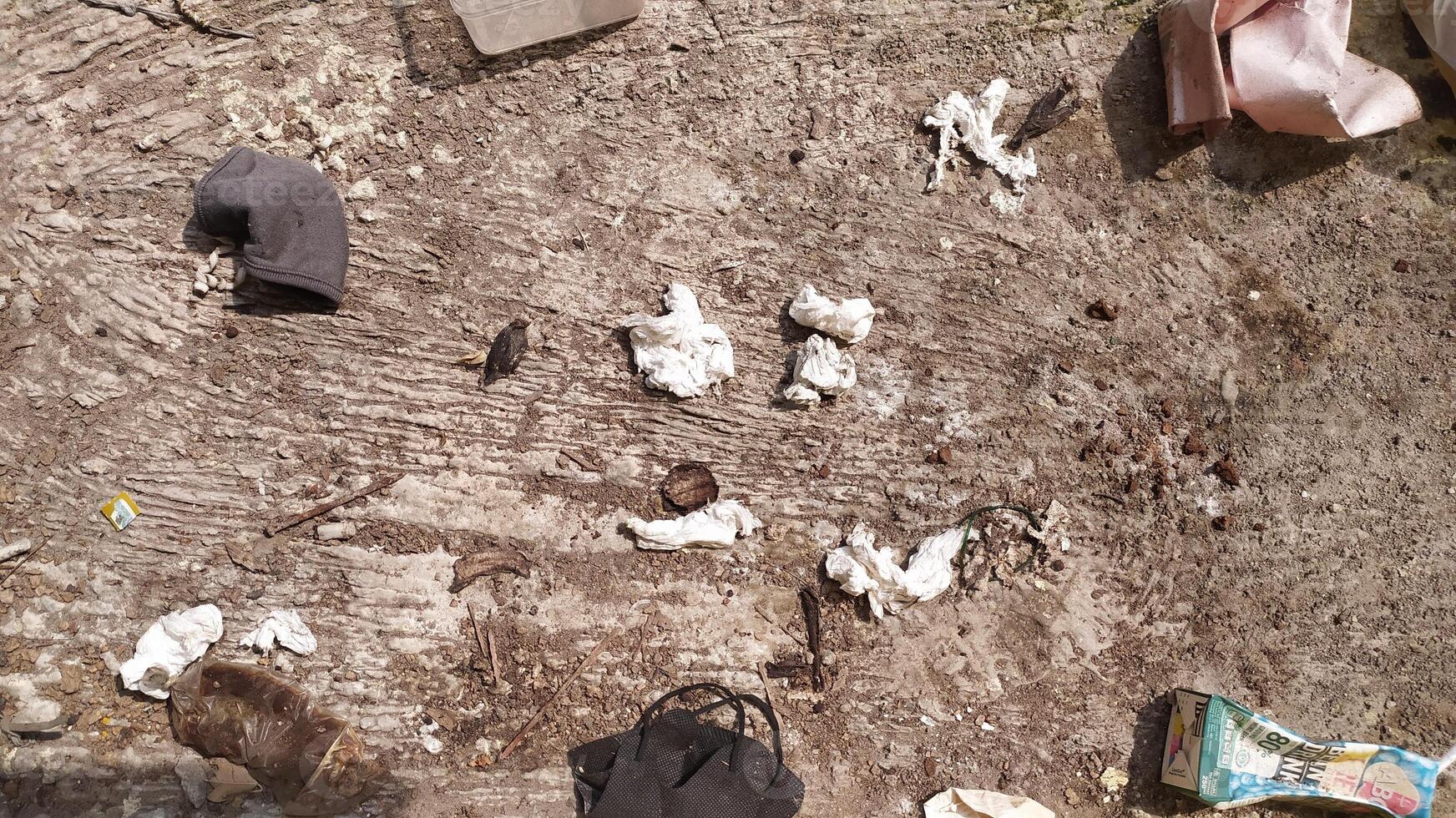 The surface of the ground is full of tissue waste scattered everywhere accompanied by dust stuck to the floor. very suitable for the background of a cleanliness campaign photo