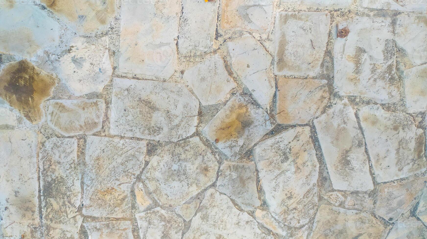 The texture of a road is made from rough-textured stone tiles with different shape variants and is dominated by cream and white colors, very suitable for background and texture design. photo