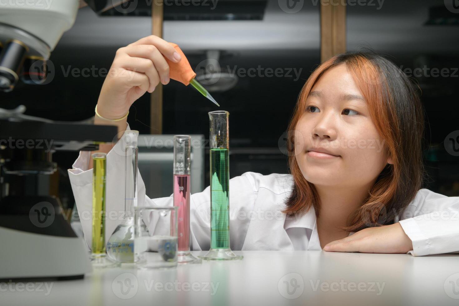 girl scientist loads liquid sample into test tube with plastic pipette. education and science photo