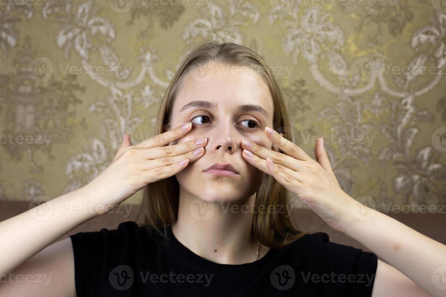 Young girl massages her face with hands for skin care, warming up the facial tissues of girl for beauty procedure photo