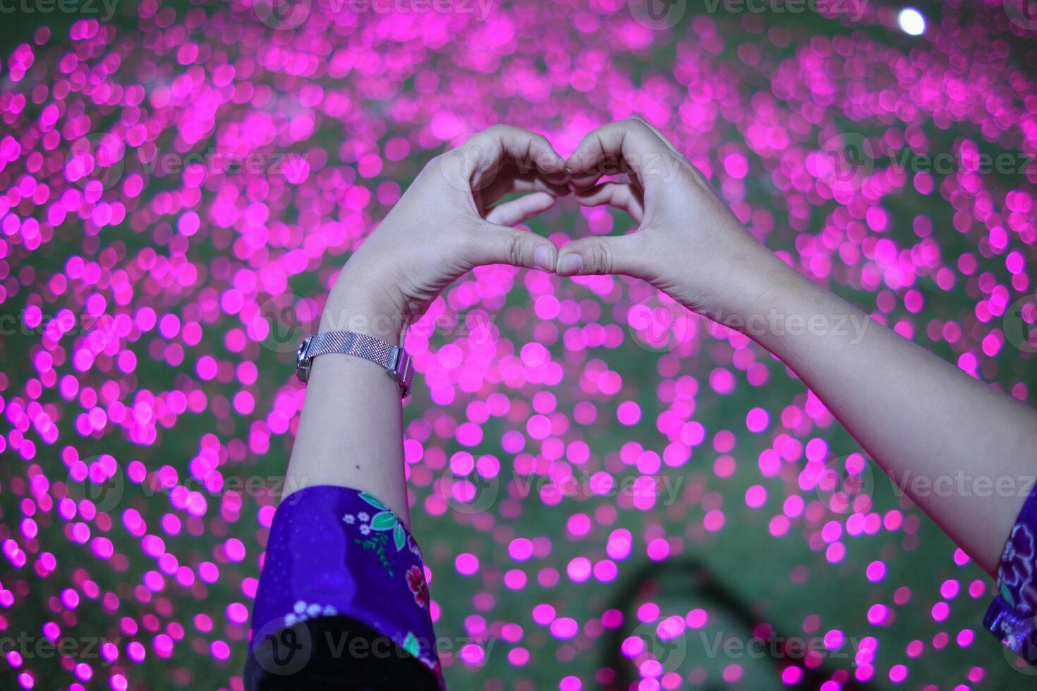 woman raises her hands make heart symbol that represents love and friendship on blurry background using hands make heart symbol represents meaning of friendship love and kindness photo