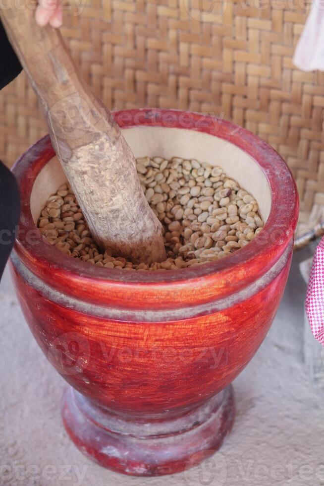 Farmers use wooden mortars and pestles to break the husks apart from the coffee beans to remove unwanted husks from coffee beans before processing them to produce high quality coffee beans for export. photo