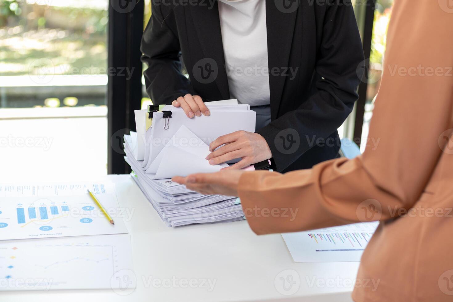 A pile of documents that the secretary has prepared for meetings of the company board of directors and investors. Many documents were arranged and prepared in piles on the desk in the secretary office photo