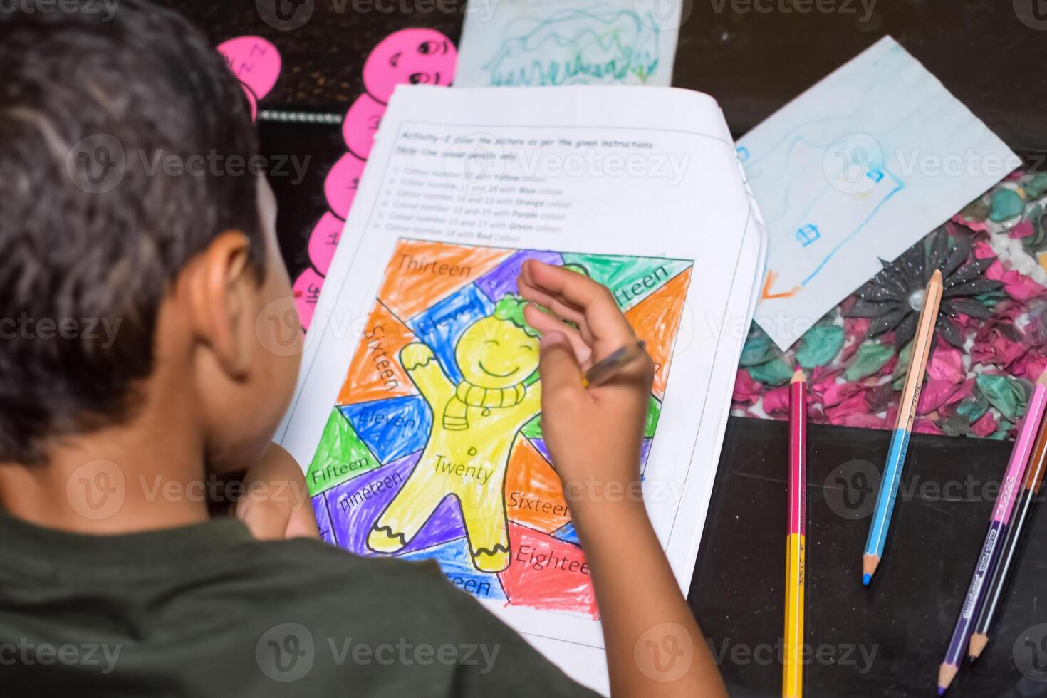 Smart Indian little boy drawing with colourful pencils kit of various colours during the summer vacations, Cute Indian Kid Sketching colourful drawing on wooden table photo