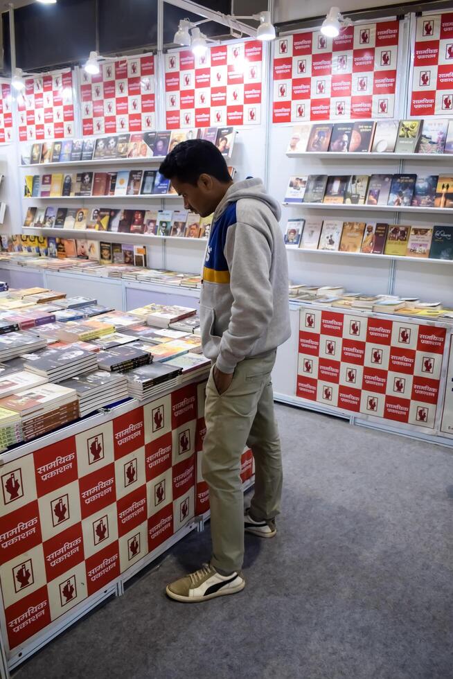 Delhi, India, June 17 2024 - Various age group people reading variety of Books on shelf inside a book-stall at Delhi International Book Fair, Books in Annual Book Fair at Bharat Mandapam complex photo
