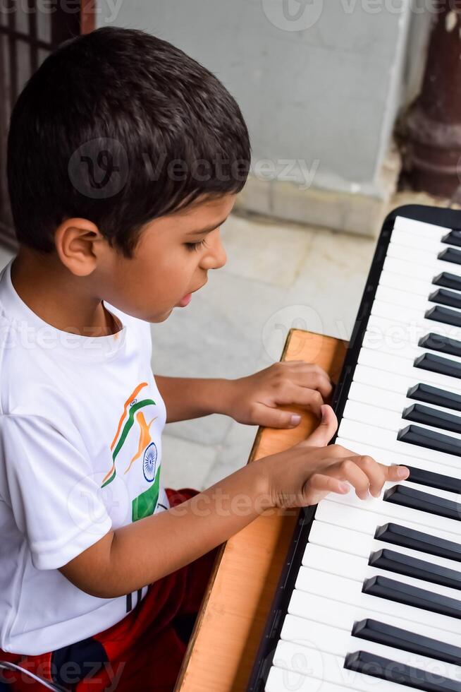 Asian boy playing the synthesizer or piano. Cute little kid learning how to play piano. Child's hands on the keyboard indoor. photo