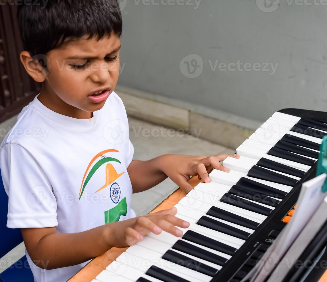 Asian boy playing the synthesizer or piano. Cute little kid learning how to play piano. Child's hands on the keyboard indoor. photo