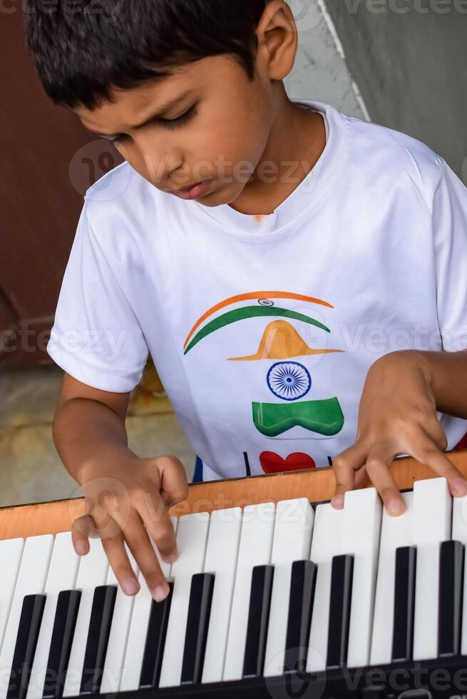 Asian boy playing the synthesizer or piano. Cute little kid learning how to play piano. Child's hands on the keyboard indoor. photo