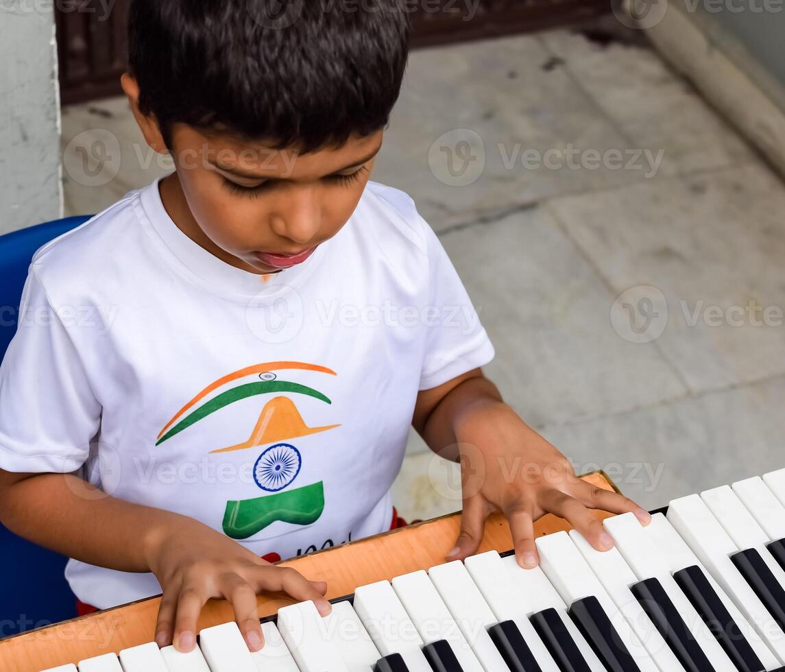 Asian boy playing the synthesizer or piano. Cute little kid learning how to play piano. Child's hands on the keyboard indoor. photo