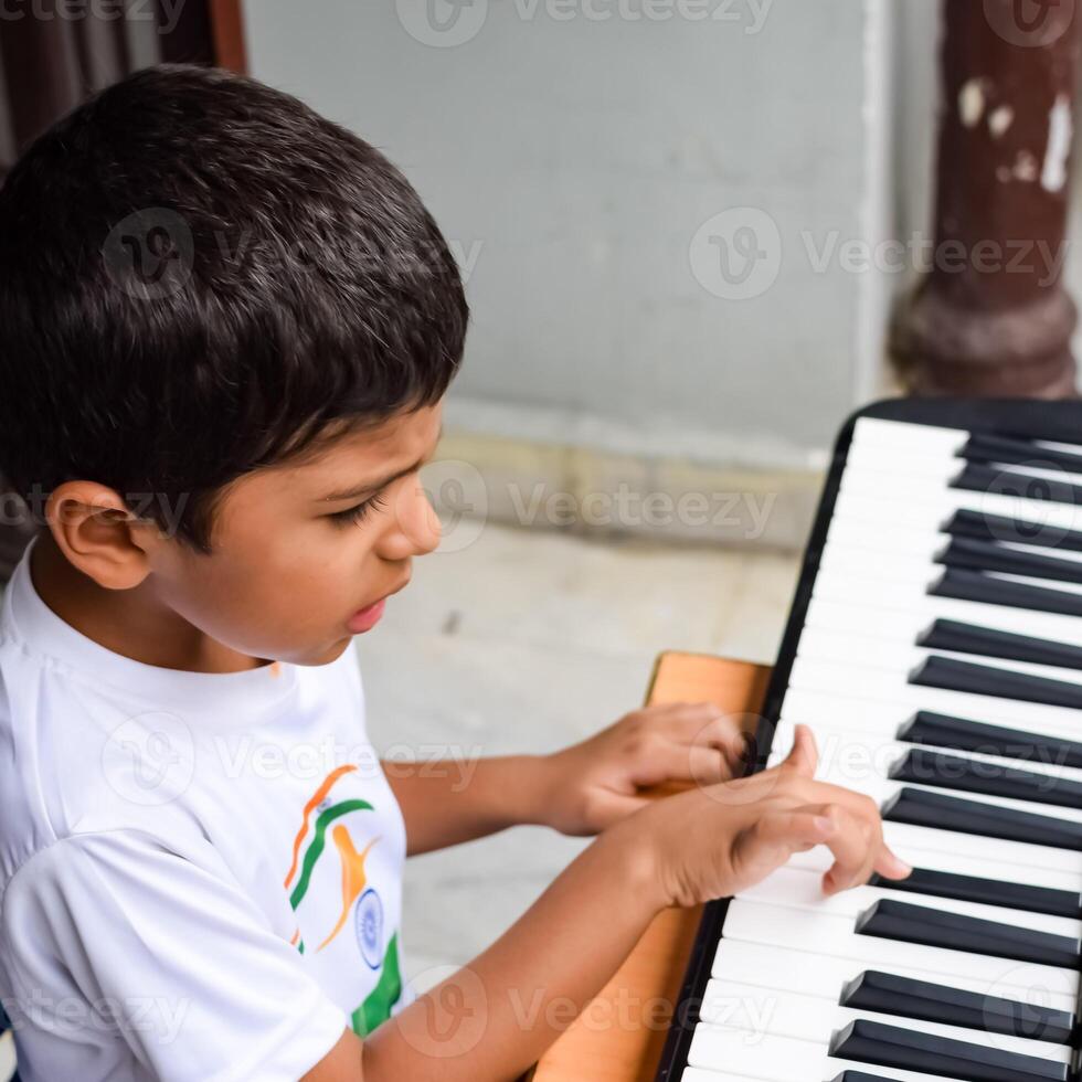 Asian boy playing the synthesizer or piano. Cute little kid learning how to play piano. Child's hands on the keyboard indoor. photo
