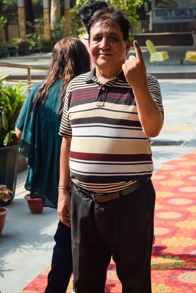 New Delhi, India - May 25 2024 - Unidentified people showing their ink-marked fingers after casting votes in front of polling booth of east Delhi area for general Lok Sabha Elections 2024 photo
