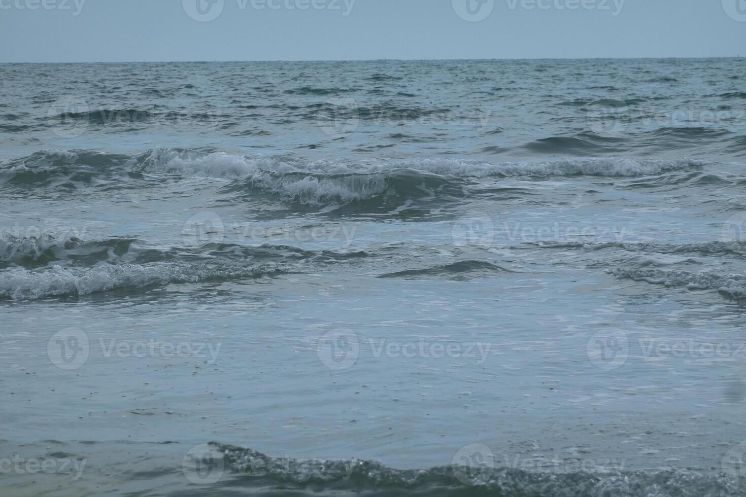 Ocean waves crash onto a sandy beach photo