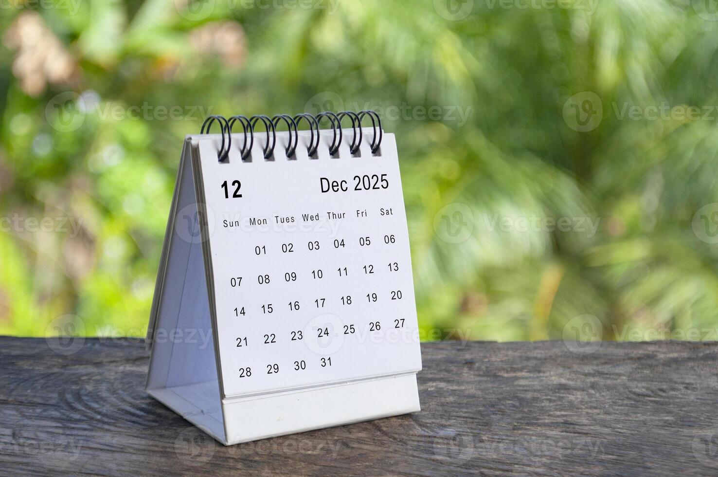 December 2025 white table calendar with outdoor background. Calendar