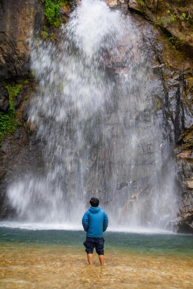 a man stand in front of beautiful waterfall name's Jok ka din in Kanchanaburi province, Thailand. subject is blurred. photo