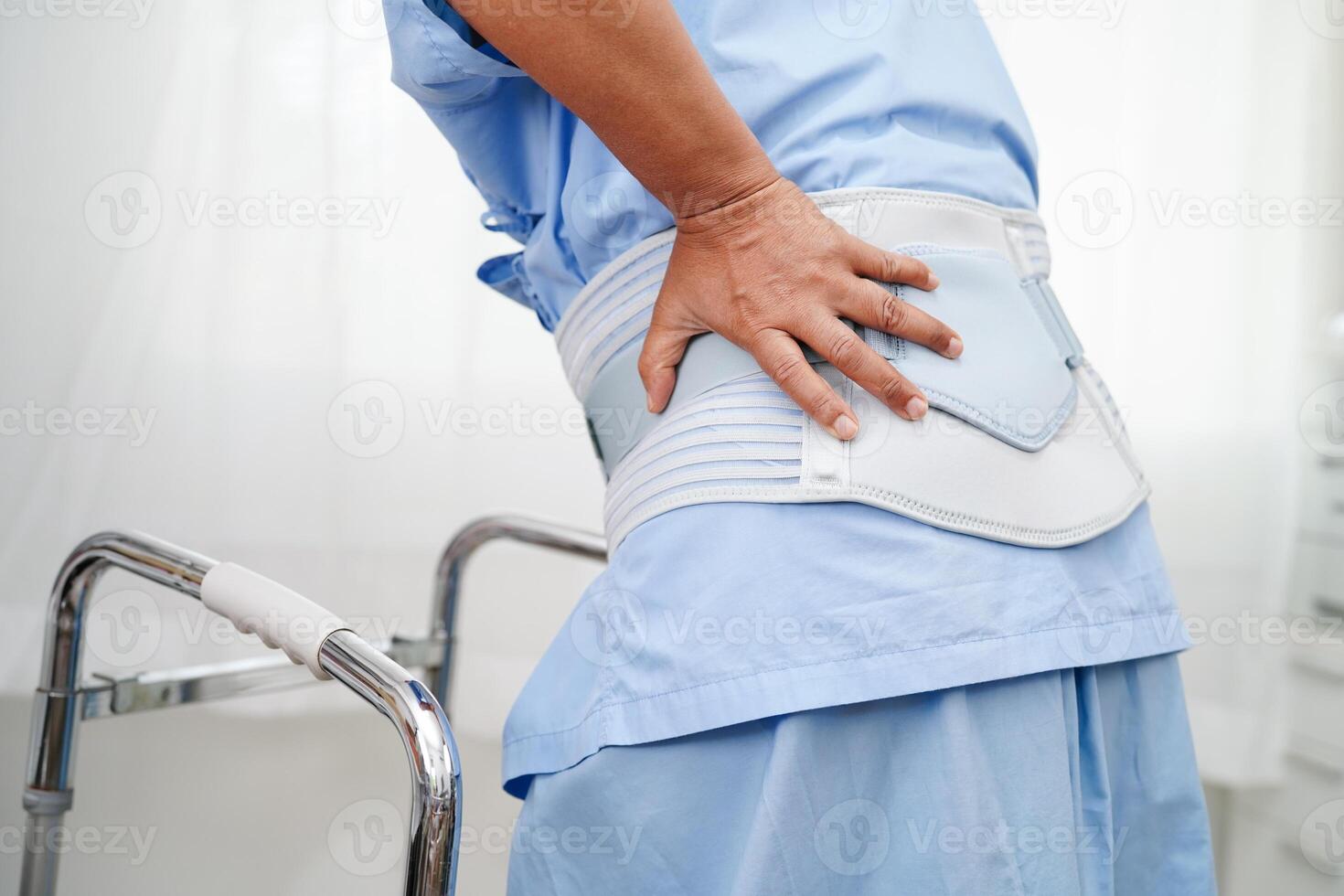 Asian senior pain back wearing elastic support belt with walker. photo
