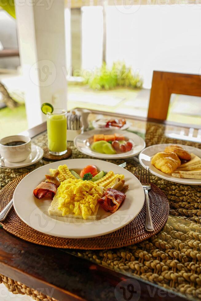 Breakfast at hotel style at Asian style hotel by the swimming pool. Table with delicious food by the beautiful blue pool travel in resort on sunny summer day. Rest and vacation in luxury hotel photo