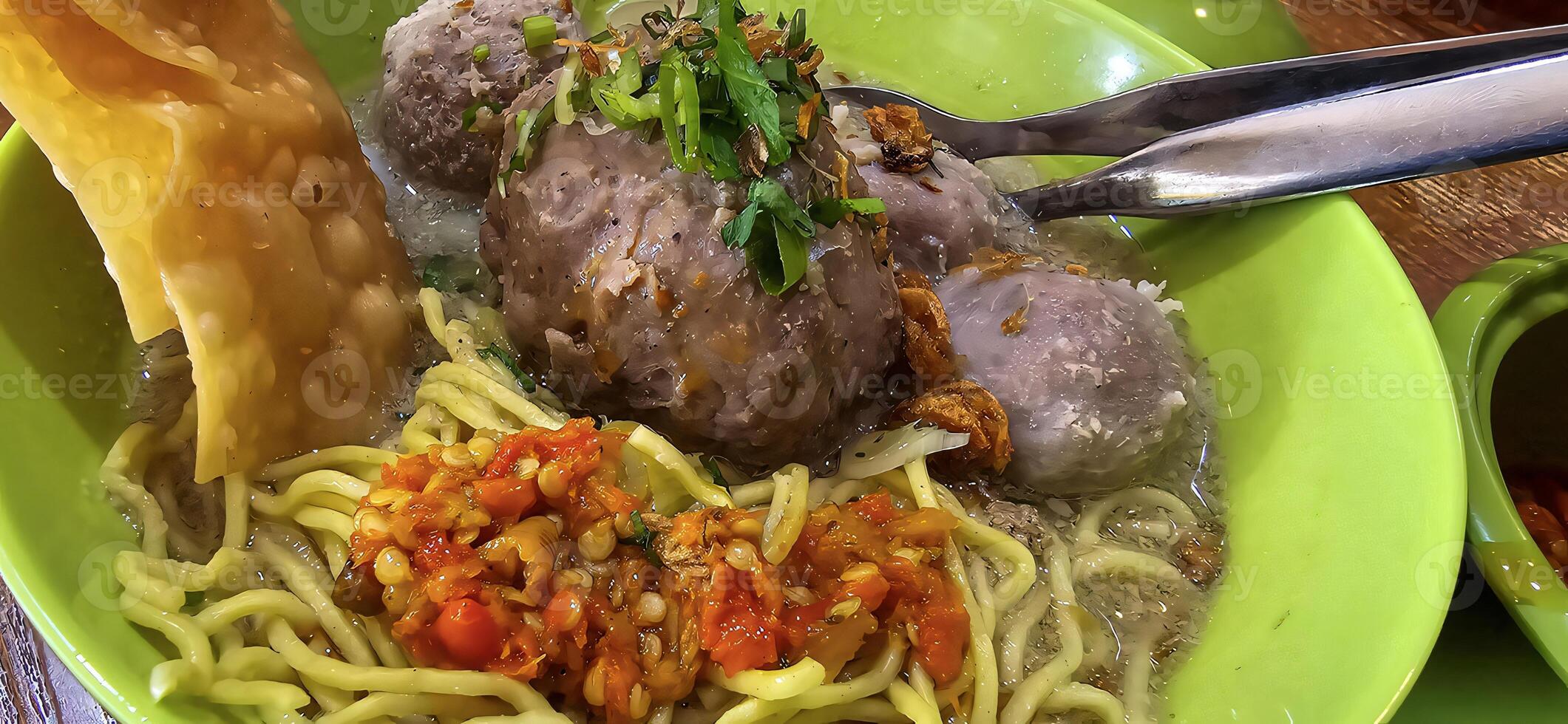 Giant Bakso, or Jumbo meatball is indonesian meatball style served with beef broth soup and noodle springkled with fried onion and spring onion coupled with chili sauce on the top photo