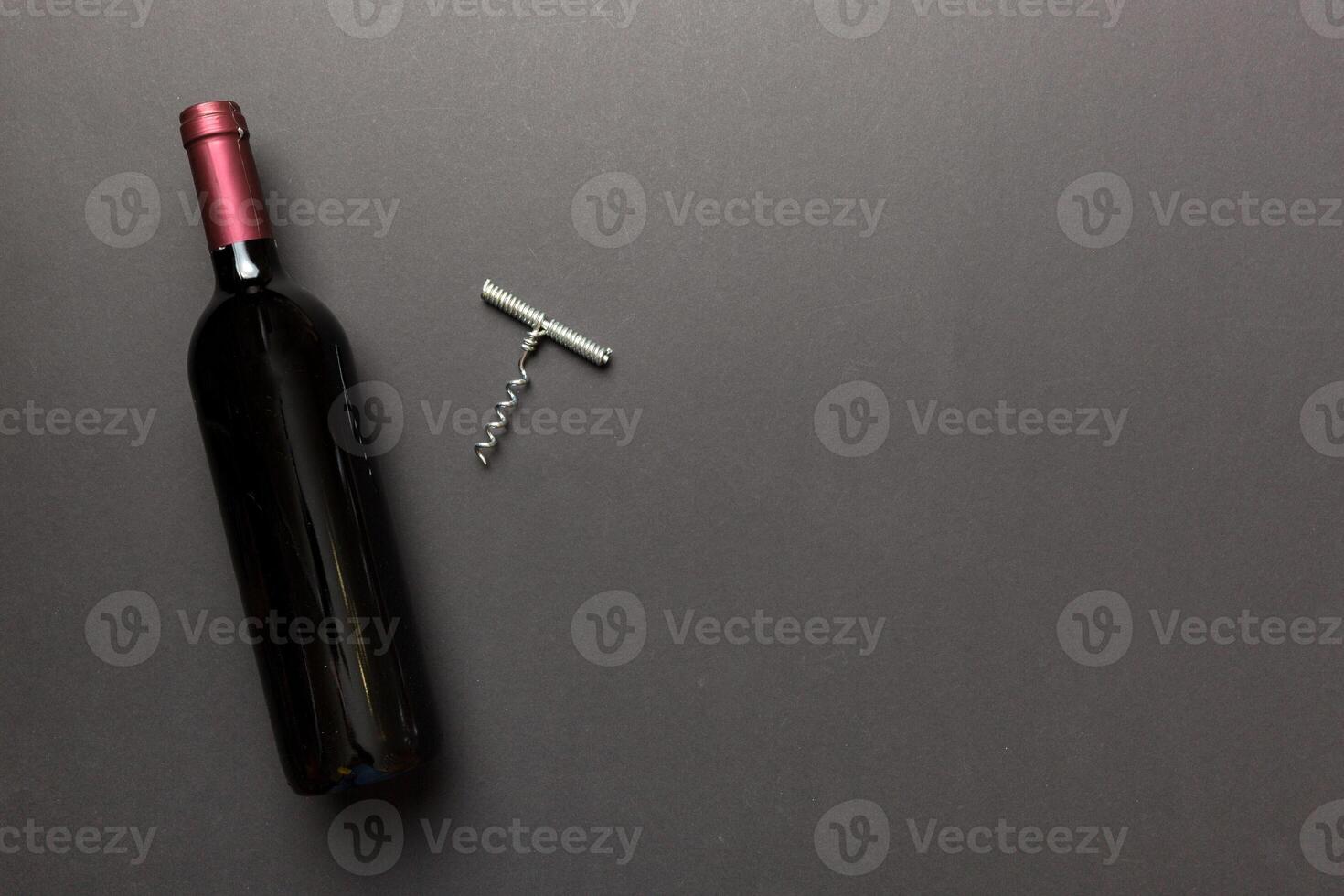 One Bottle of red wine with corkscrew on colored table. Flat lay, top view wth copy space photo