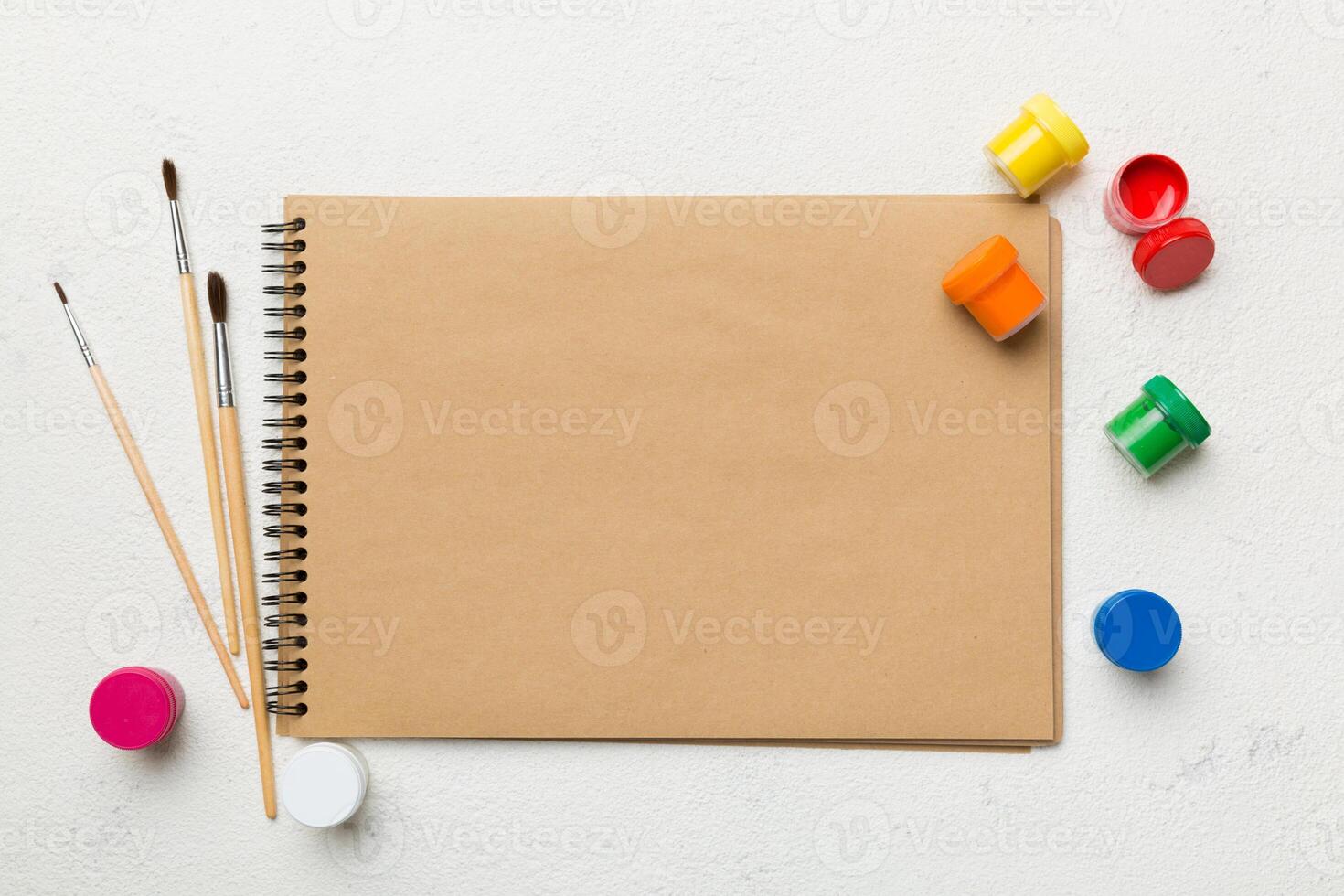 Album pages and paints, pencils, brush on a colored background. Top view with empty space. workplace for creativity. home teaching concept drawing photo