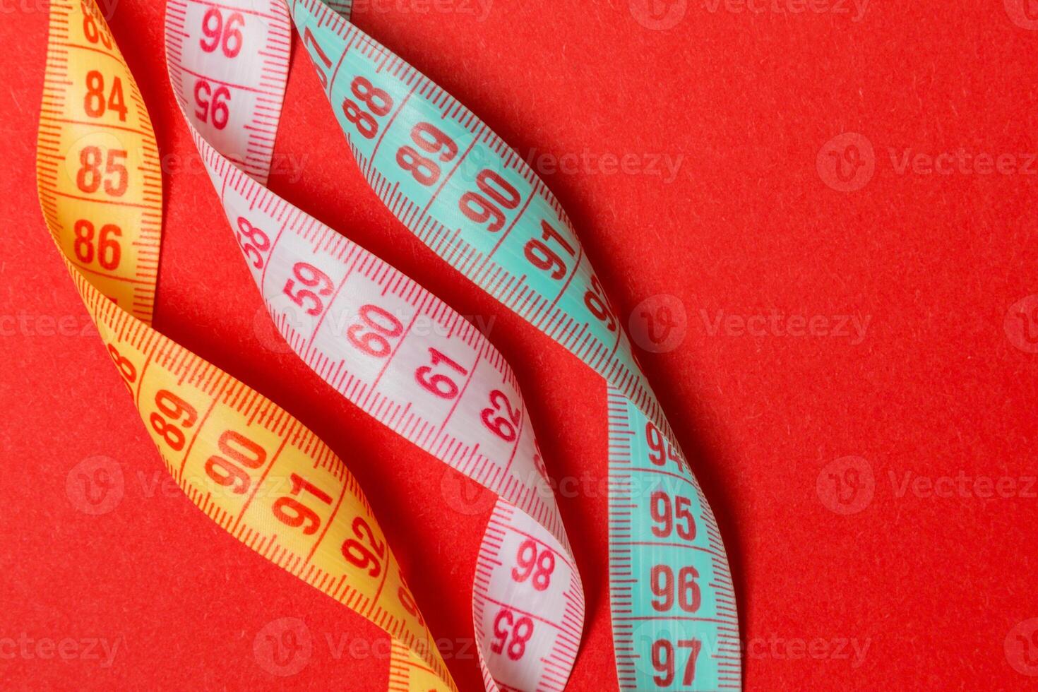 Close up of colorful measure tapes on red background. Perfect female figure measurements concept photo