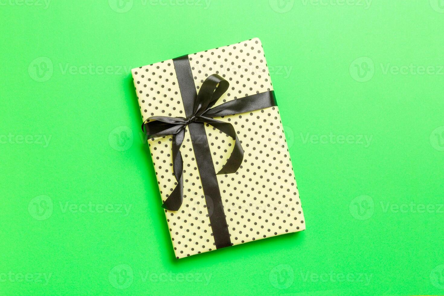 Top view Christmas present box with black bow on green background with copy space photo