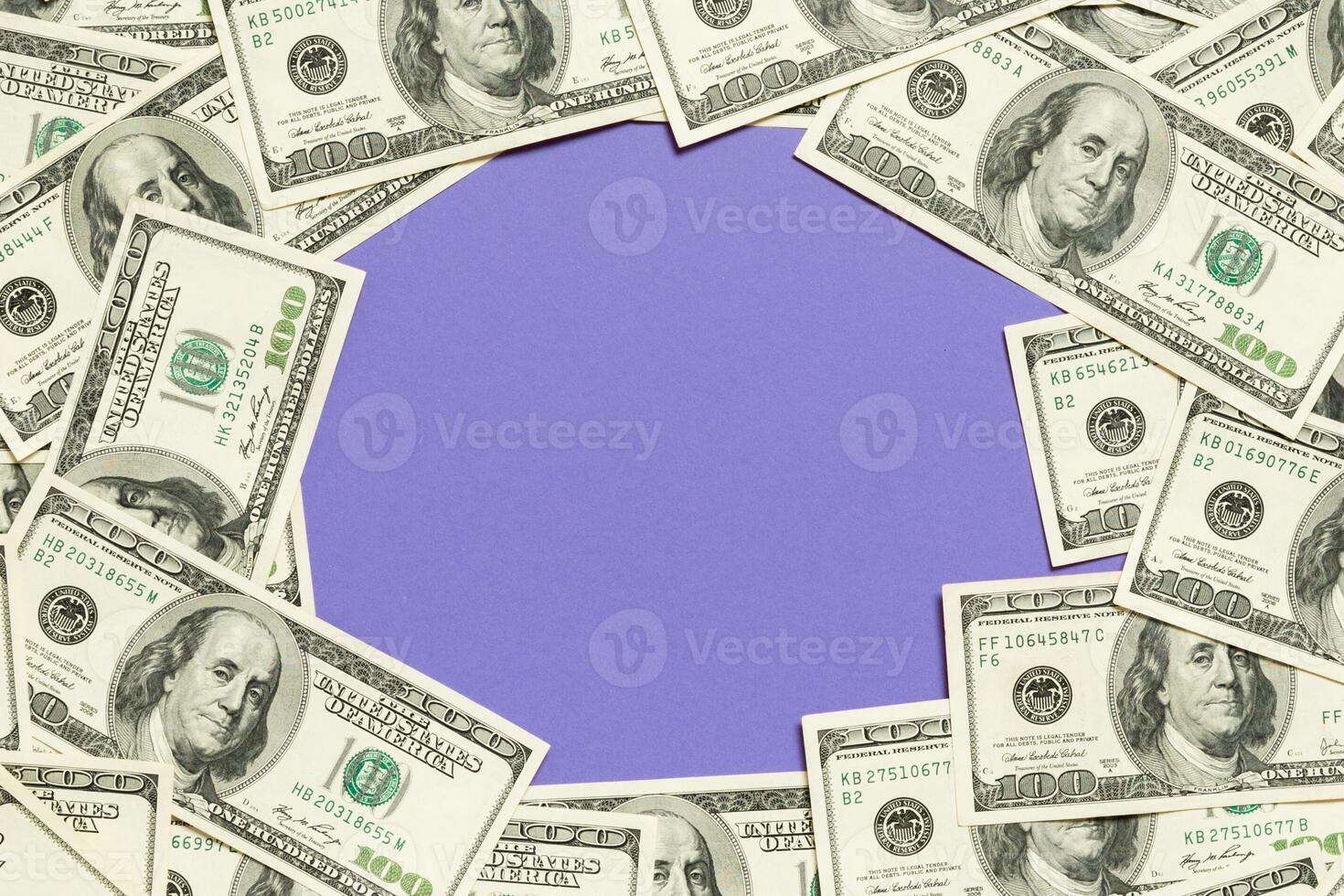 Frame made of dollars with copy space in the middle. Top view of business concept on purple background with copy space photo
