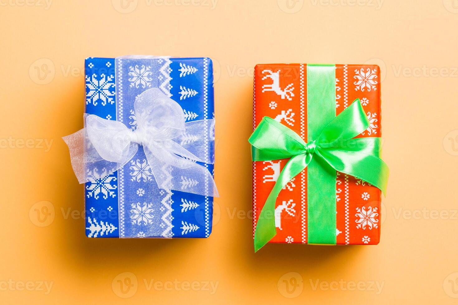 wrapped Christmas or other holiday handmade present in paper with white and green ribbon on orange background. Present box, decoration of gift on colored table, top view photo