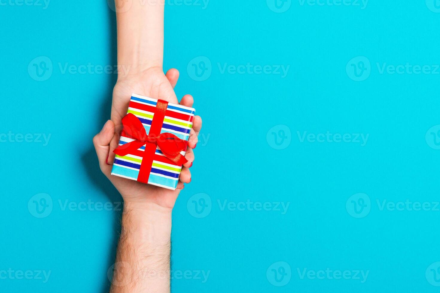 Top view of a gift in male and female hands on colorful background. Congratulation of each other concept. Copy space photo