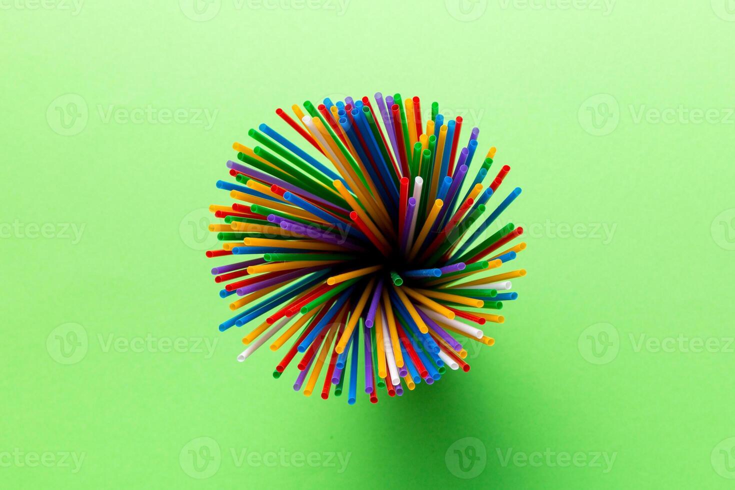 Top view of many multicolored plastic cocktail tubes in a glass. Drinking straws of bright colors Isolated on white background photo