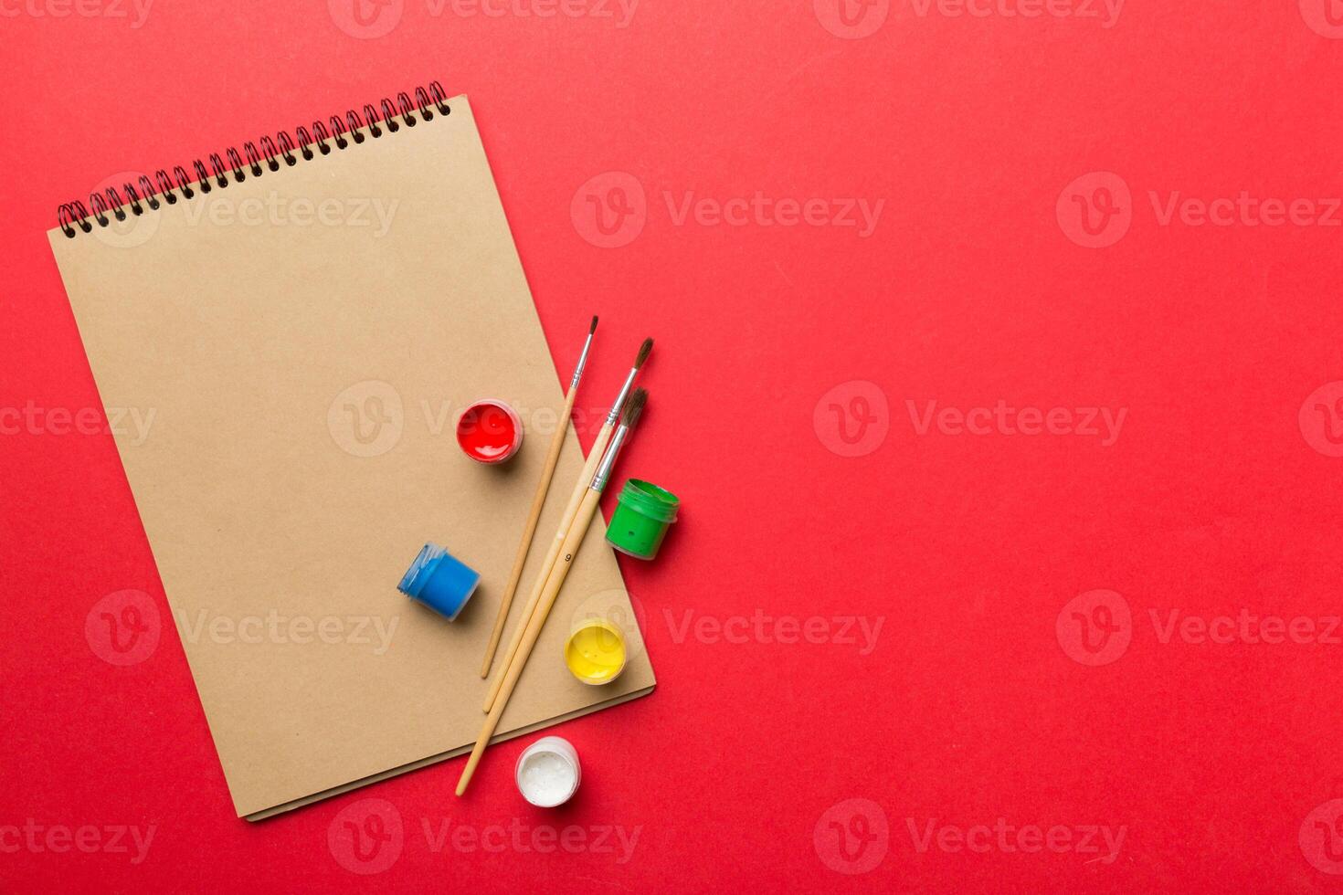 Album pages and paints, pencils, brush on a colored background. Top view with empty space. workplace for creativity. home teaching concept drawing photo