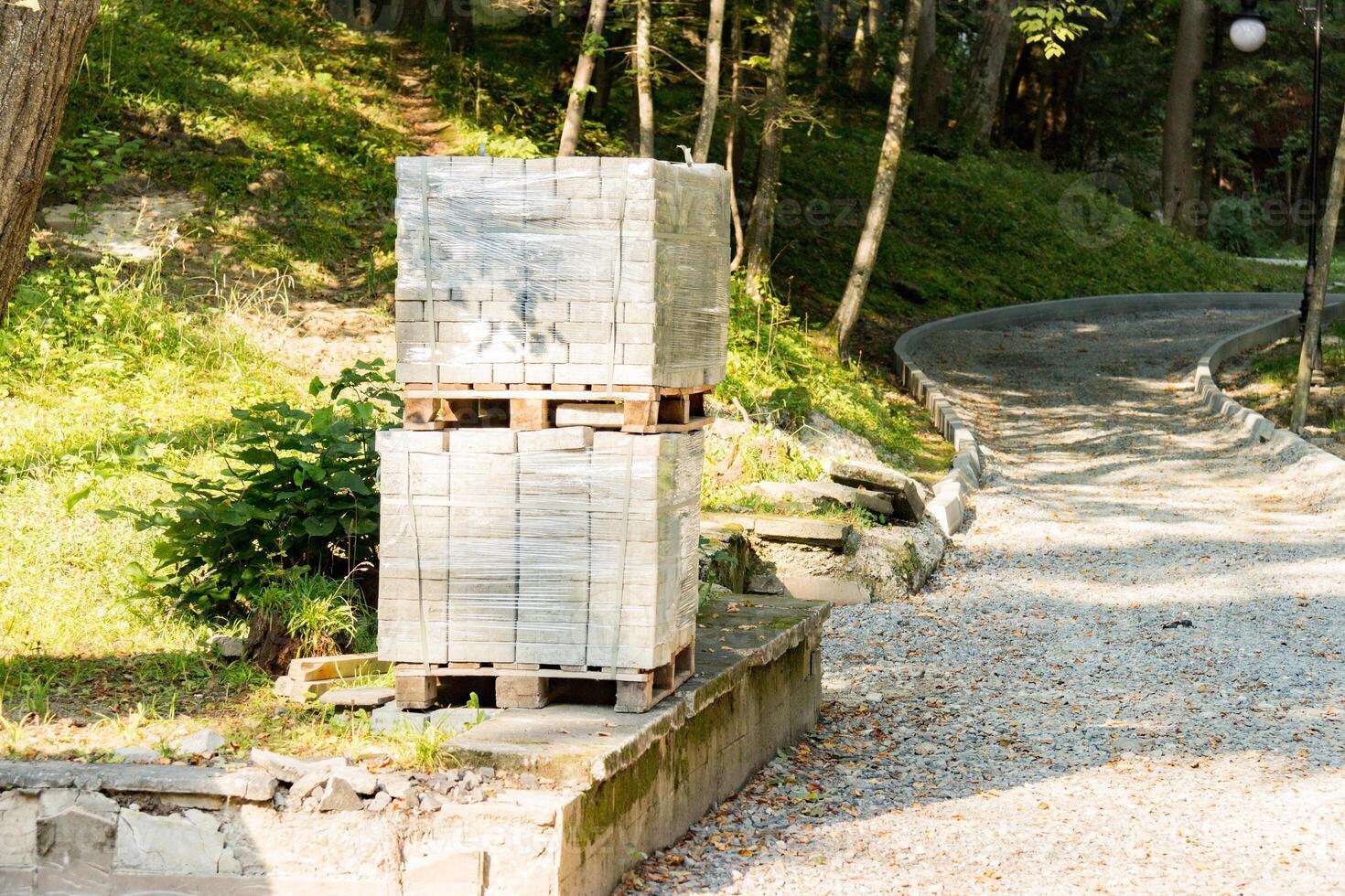 Pile of concrete paving slabs on a wooden pallet. Blocks for paving a sidewalk in the park photo