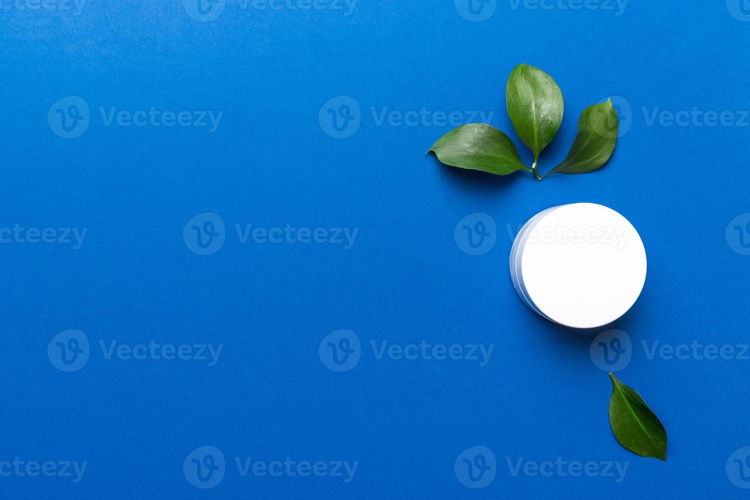 Organic cosmetic product with green leaves on color background. Copy space, flat lay photo
