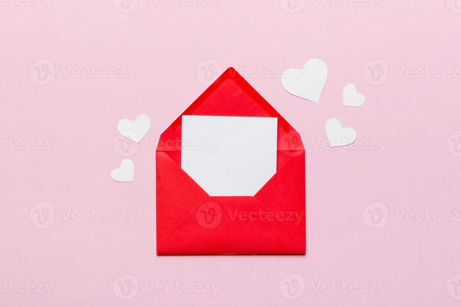Red paper envelope with empty white card and heart on colored background. top view valentines day concept photo