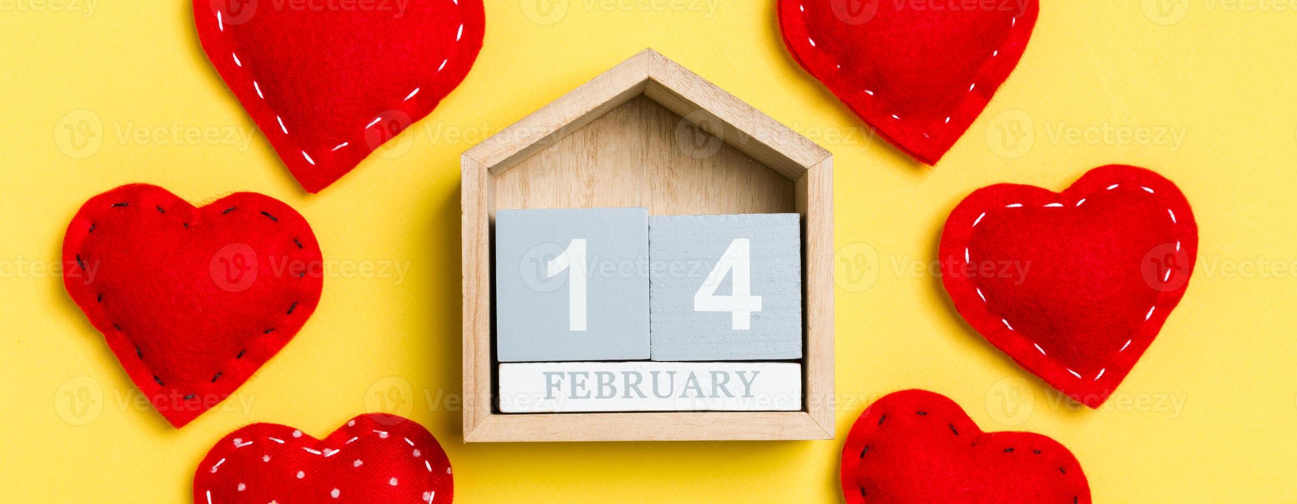 Top view of wooden calendar and textile hearts on colorful background. The fourteenth of February. Valentine's day concept photo