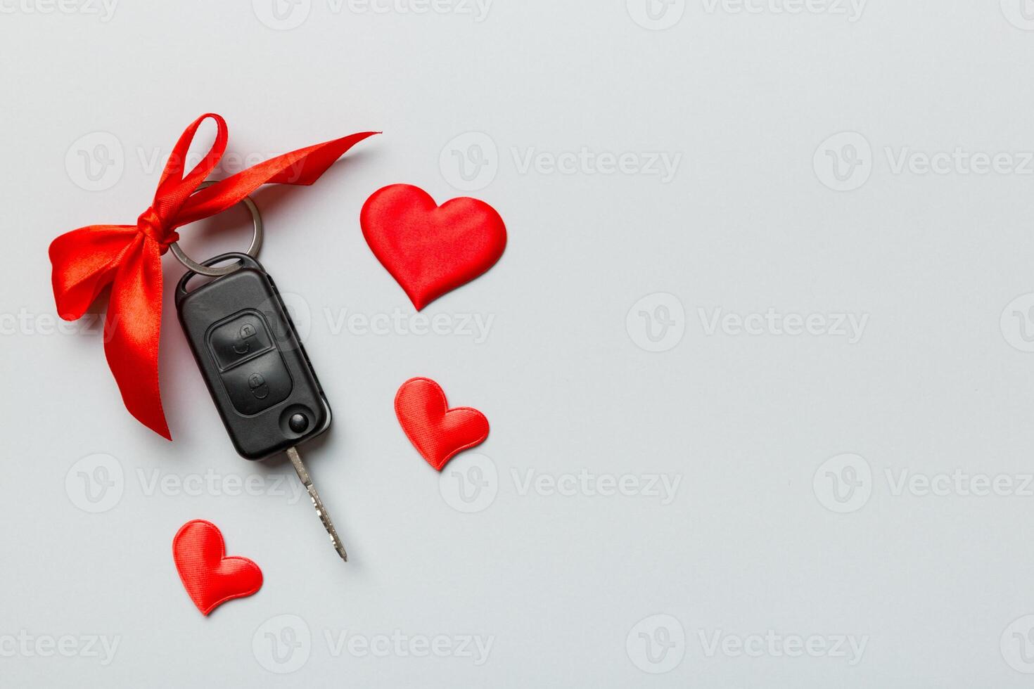 Car key with a red bow and a heart on Colored table. Giving present or gift for valentine day or christmas, Top view with copy space photo