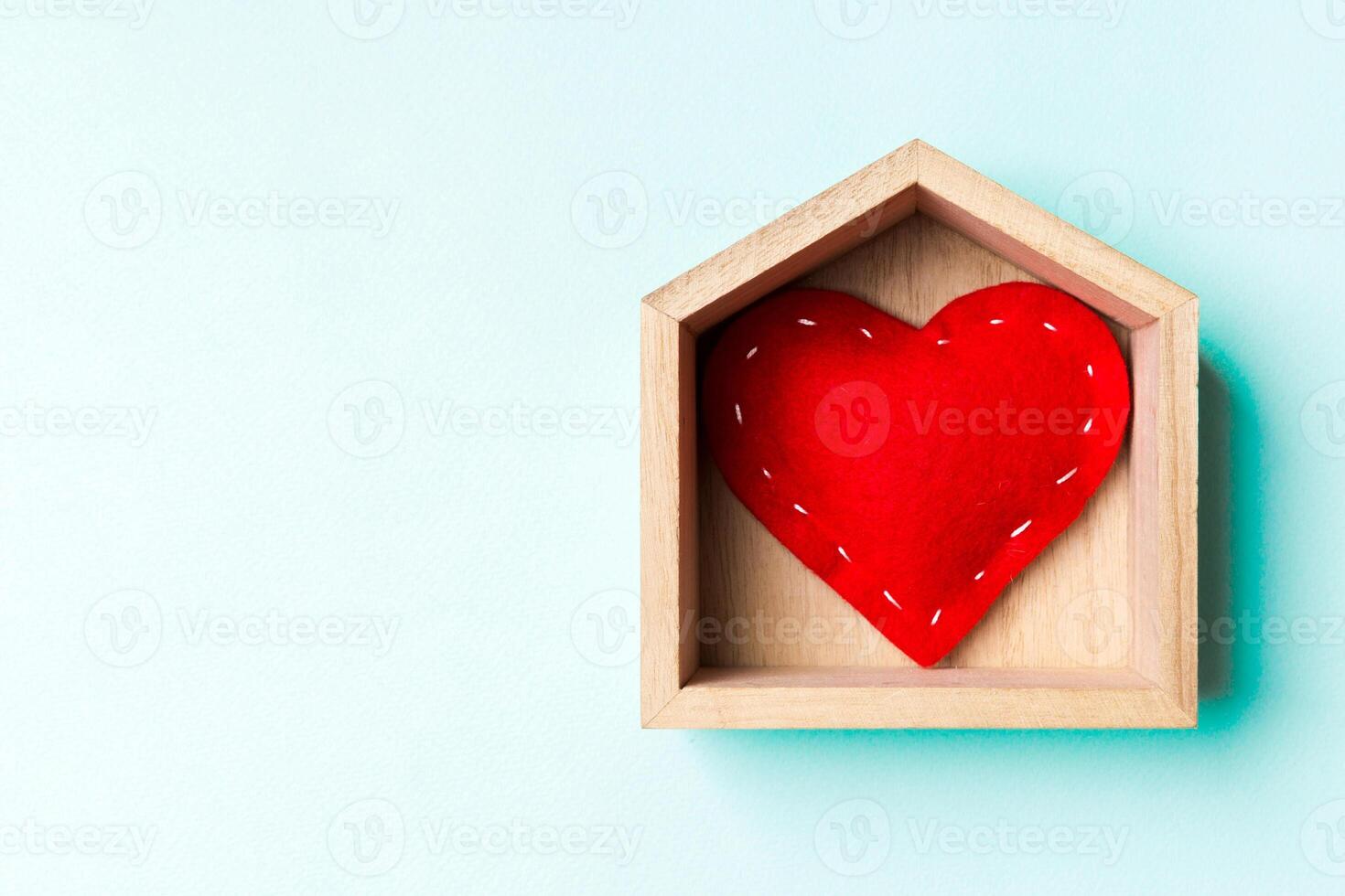 Top view of red textile heart in a wooden house on colorful background. Home sweet home concept. Valentine's day photo