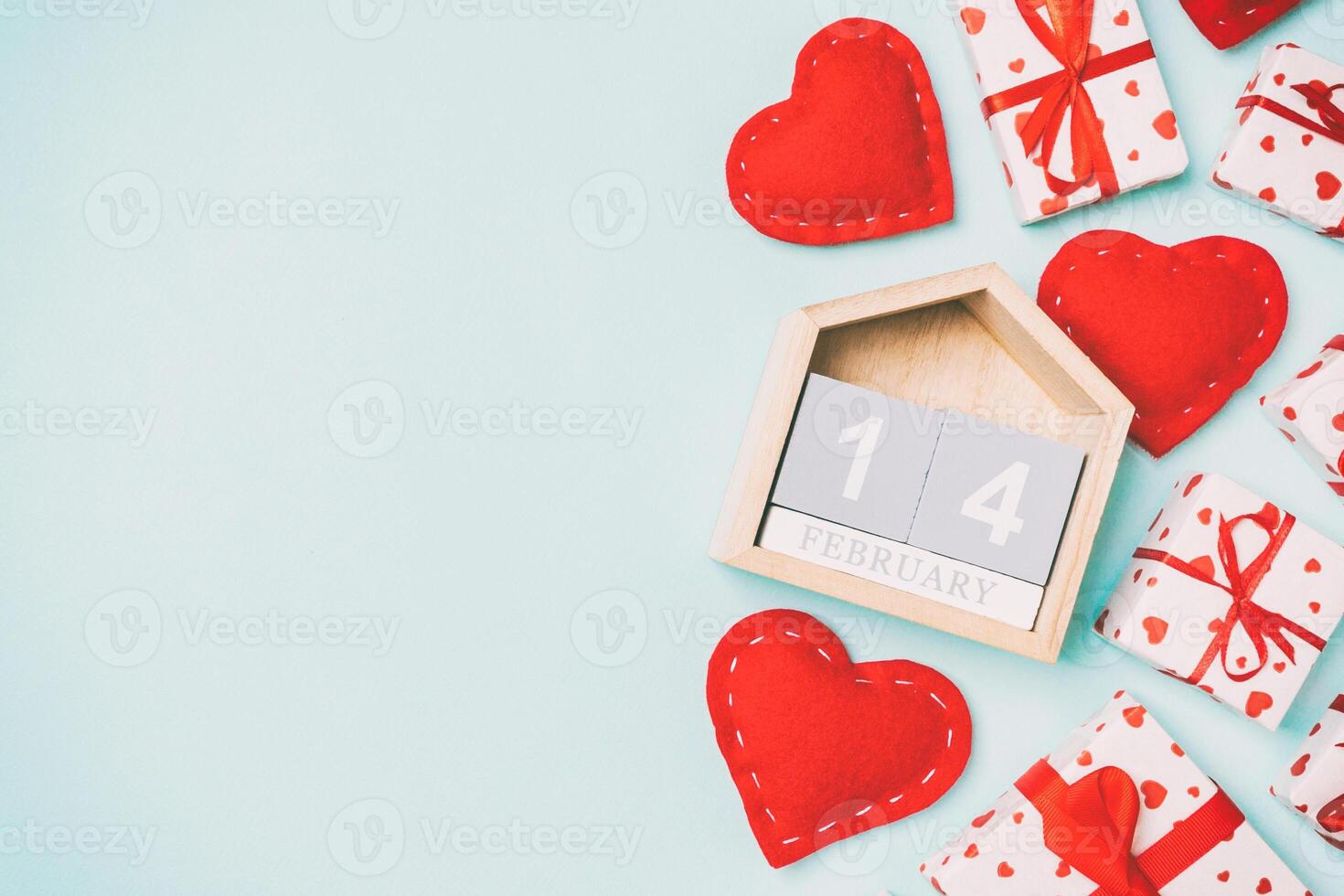 Holiday composition of gift boxes, wooden calendar and red textile hearts on colorful background with empty space for your design. The fourteenth of February. Top view of Valentine's Day concept photo