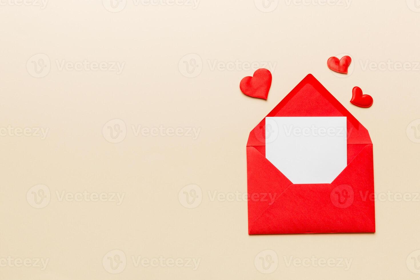Red paper envelope with empty white card and heart on colored background. top view valentines day concept photo