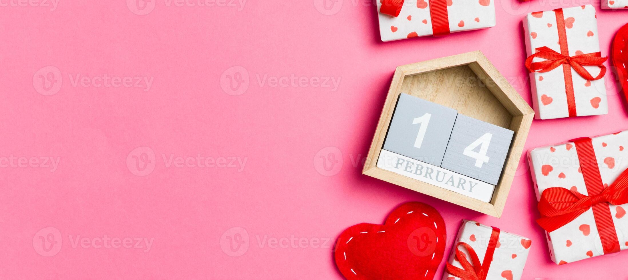 Holiday composition of gift boxes, wooden calendar and red textile hearts on colorful background with empty space for your design. The fourteenth of February. Top view of Valentine's Day concept photo