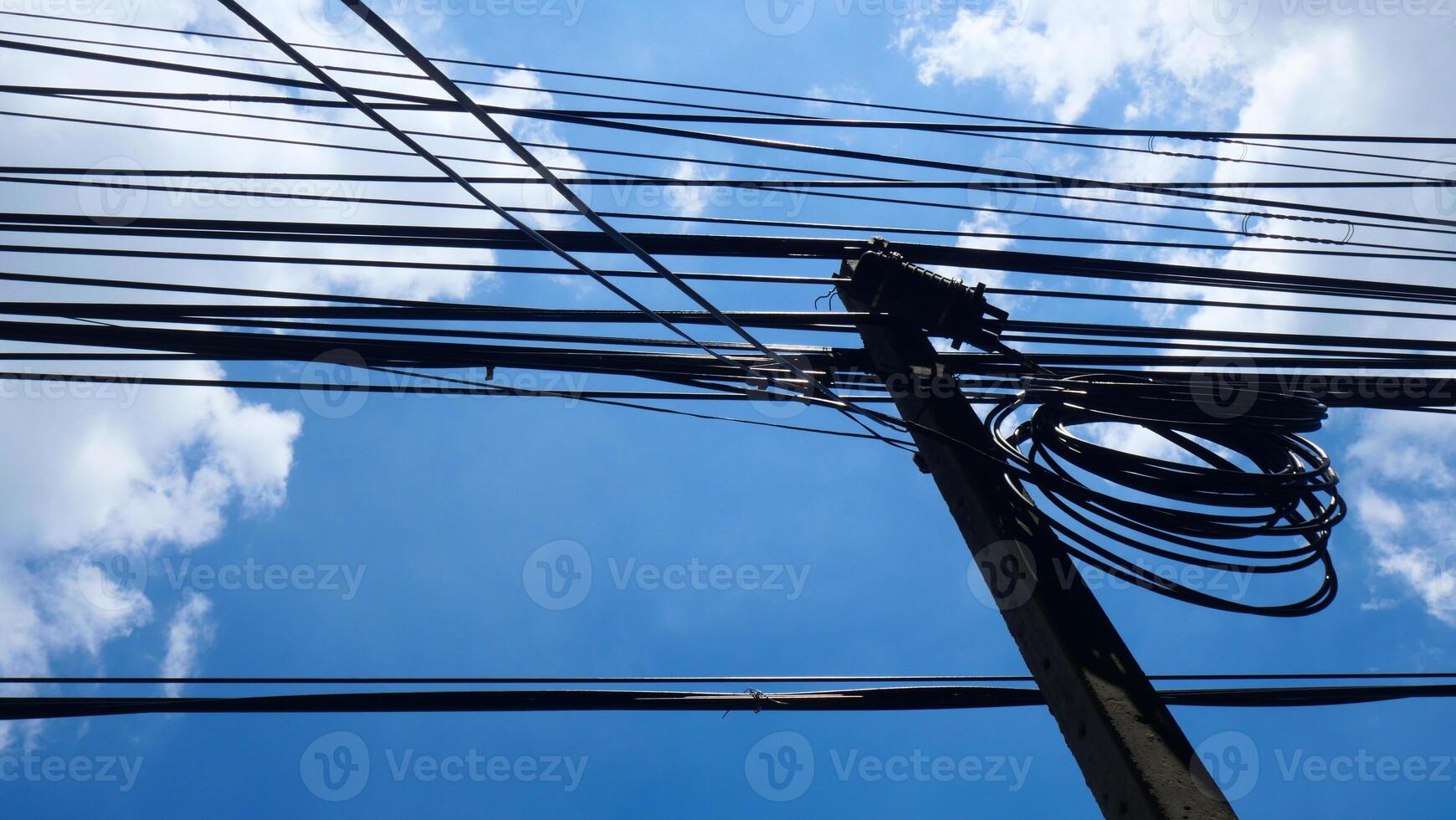Electrical poles and electrical wires on the side of the road There is a blue sky and clouds in the background photo