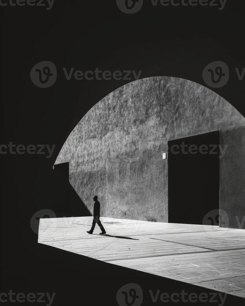 A person walking through a tunnel their shadow merging with the darkness and leading them towards an unknown destination. Black and white art. photo