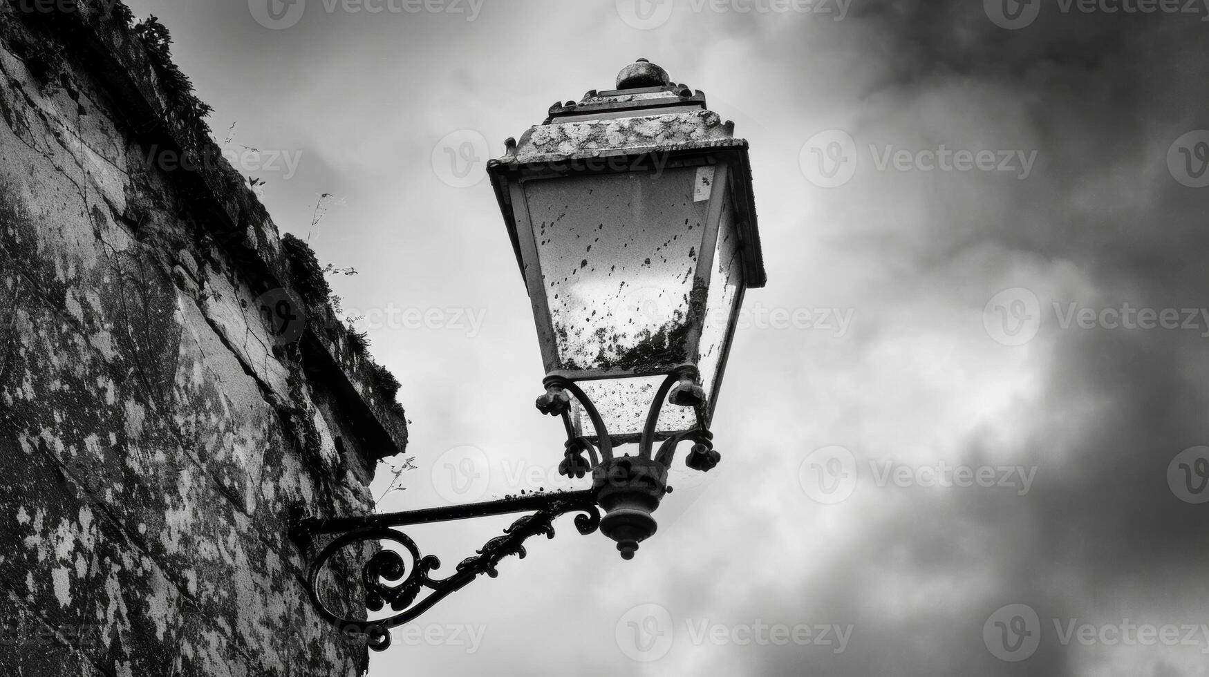 The vintage street lamp stands proudly despite its chipped and tarnished surface. Black and white art. photo