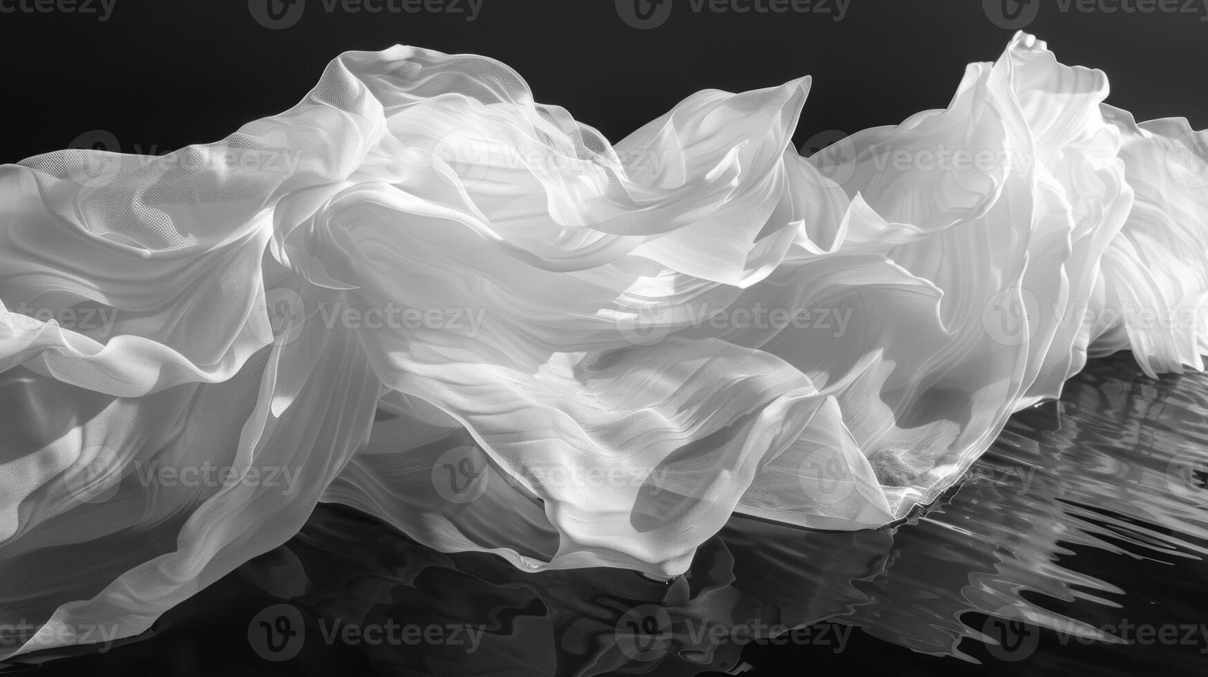 The rippling waves of a lake contrast with the stillness of the windblown fabric floating atop it. Black and white art. photo