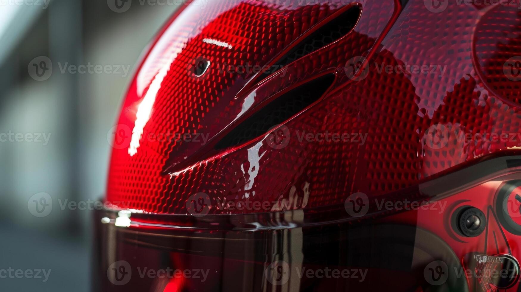 A closeup of a bright red helmet with intricate mesh detailing on the front emphasizing both style and ventilation photo