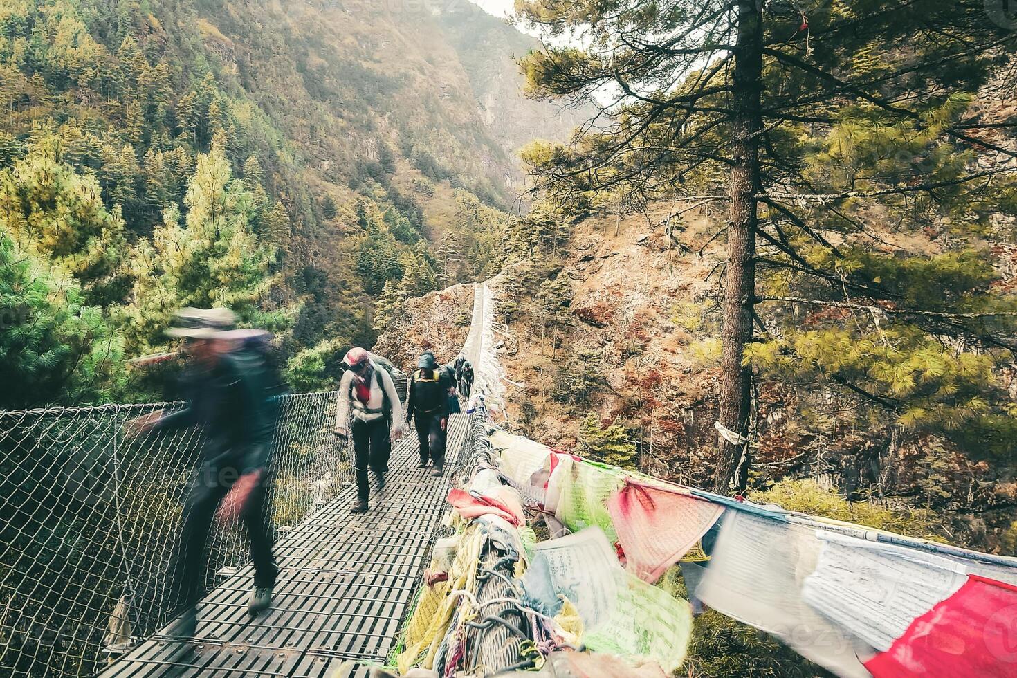 Close up people trekkers walk over pass crossing famous Hillary suspension bridge on way to Everest base camp. EBC trek. Popular challenging trek Himalayas outdoors in Nepal photo