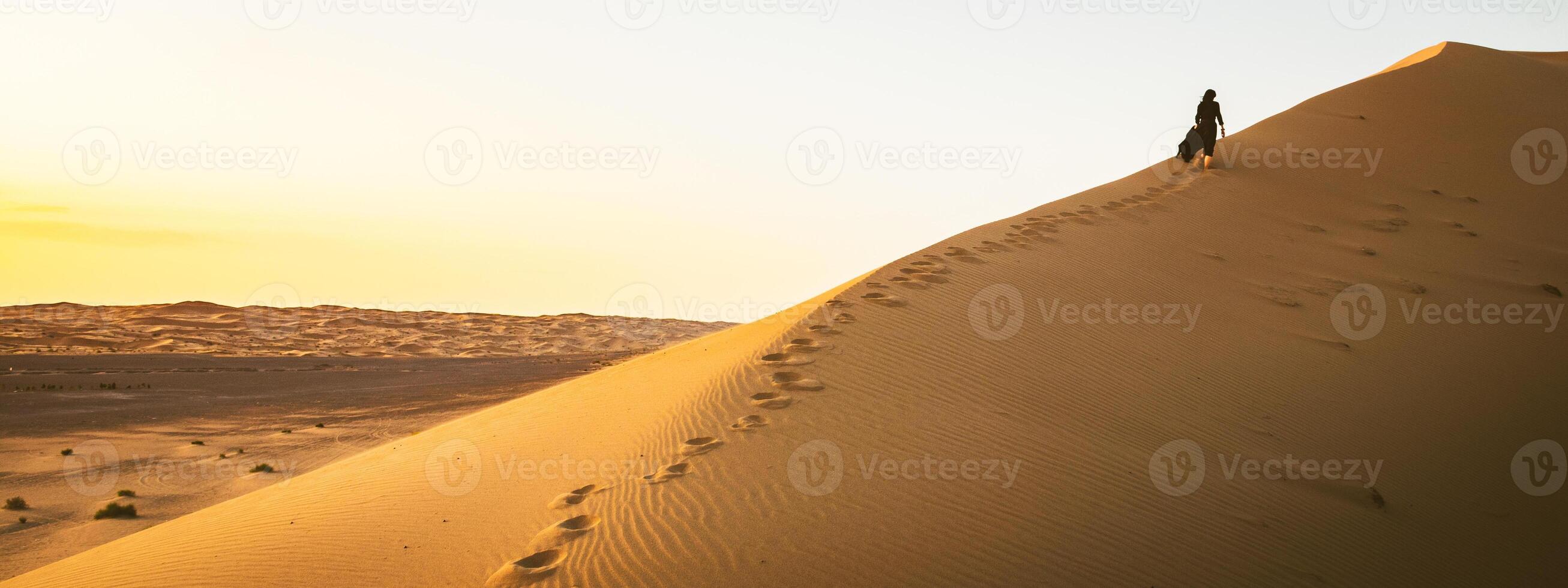 Young beautiful woman in long dress walks along sand dunes in iran KAshan desert photo