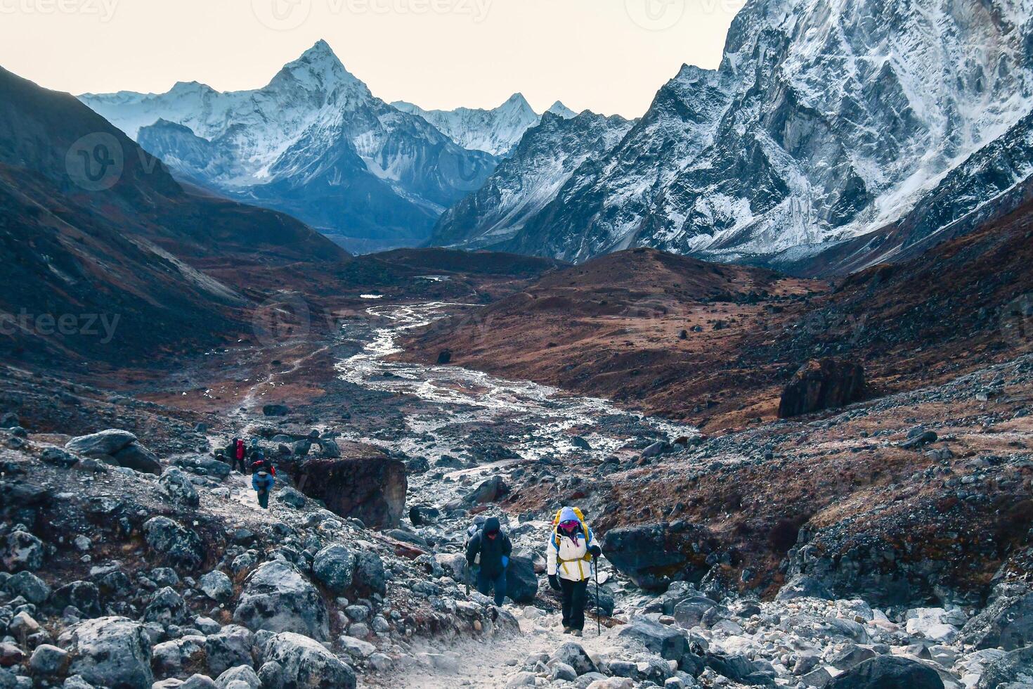 Group of trekkers trekking in Himalayas mountains through Cho la glacier and pass. to Gokyo Ri. Nepalese male guide leading tourist client in Sagarmatha national park official trek photo